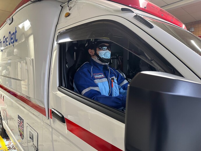 サングラスを着用して救急車を運転する救急隊員